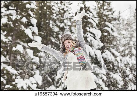 Picture - USA, Utah, Salt Lake City, young woman in winter clothing throwing snow in air. Fotosearch