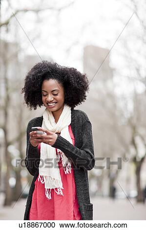 Stock Image - USA, Washington State, Seattle, Cheerful young woman text messaging. Fotosearch