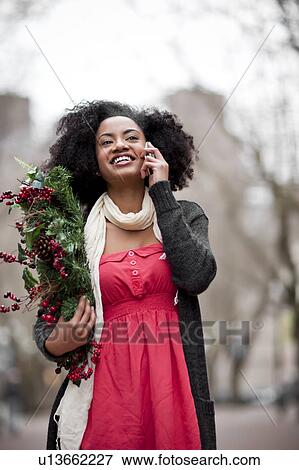 USA, Washington State, Seattle, Cheerful young woman holding christmas wreath while using mobile phone View Large Photo Image Stock Photo - USA, Washington State, Seattle, Cheerful young woman holding christmas wreath while using mobile phone. Fotosearch