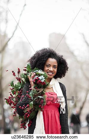 Stock Photography - USA, Washington State, Seattle, Cheerful young woman holding christmas wreath. Fotosearch
