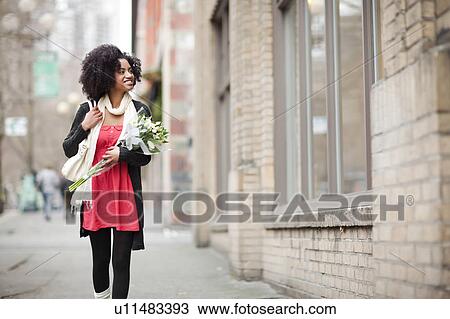 USA, Washington State, Seattle, Young woman walking in street carrying bunch of tulips View Large Photo Image Stock Image - USA, Washington State, Seattle, Young woman walking in street carrying bunch of tulips. Fotosearch