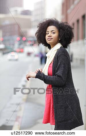 Stock Image - USA, Washington State, Seattle, young woman standing on street. Fotosearch