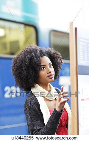 Stock Photography - USA, Washington State, Seattle, young woman looking at arrival departure board. Fotosearch