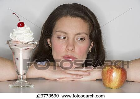 Woman choosing between ice cream and apple View Large Photo Image Stock Image - Woman choosing between ice cream and apple. Fotosearch