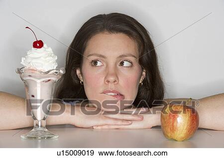 Woman choosing between ice cream and apple View Large Photo Image Stock Photo - Woman choosing between ice cream and apple. Fotosearch