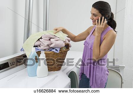 Picture - Woman doing laundry and talking on phone. Fotosearch