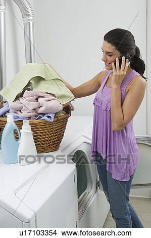 Woman doing laundry and talking on phone View Large Photo Image Picture - Woman doing laundry and talking on phone. Fotosearch
