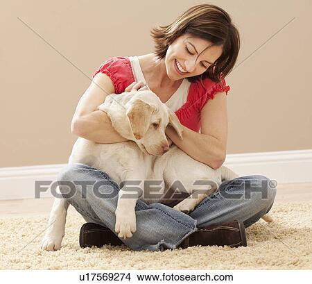 Woman embracing Labrador on carpet View Large Photo Image Picture - Woman embracing Labrador on carpet. Fotosearch
