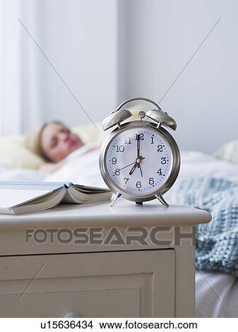 Picture - Woman in bed with alarm clock in foreground. Fotosearch