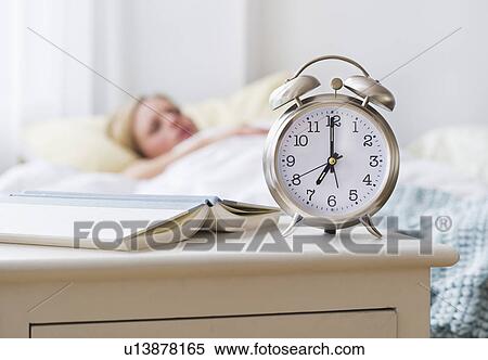 Stock Photography - Woman in bed with alarm clock in foreground. Fotosearch