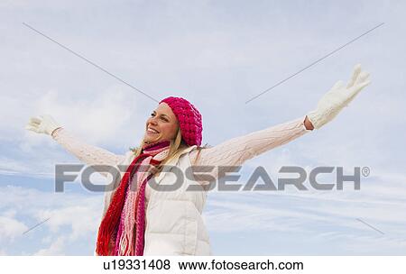 Stock Photo - Woman in winter clothing raising arms. Fotosearch