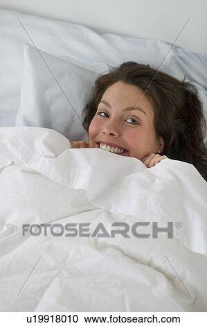 Stock Image - Woman lying in bed. Fotosearch