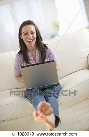 Stock Photo - Woman using laptop on sofa. Fotosearch