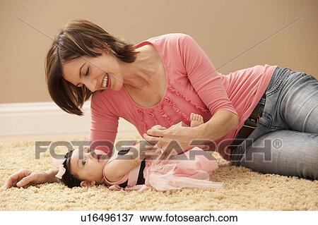 Stock Photo - Woman with baby girl (2-5months) lying on floor. Fotosearch