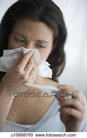 Stock Image - Woman with flu blowing nose. Fotosearch