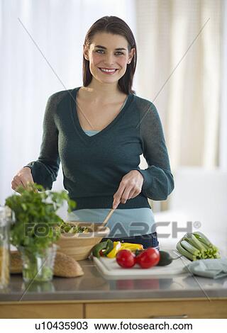 Stock Image - Young attractive woman preparing food. Fotosearch