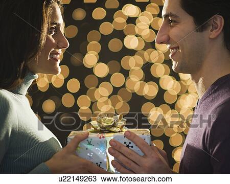Stock Image - Young couple giving Christmas presents each other. Fotosearch