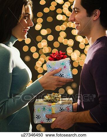 Young couple giving Christmas presents each other View Large Photo Image Stock Image - Young couple giving Christmas presents each other. Fotosearch