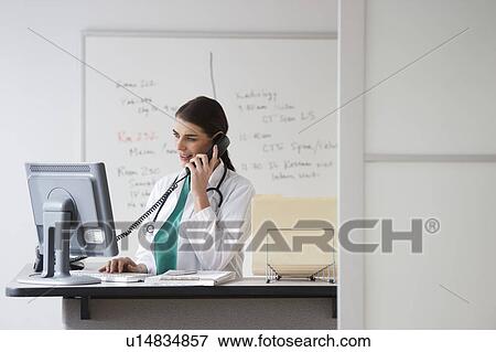 Stock Photo - Young female doctor working in office. Fotosearch
