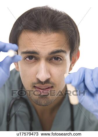 Young surgeon holding small torch in one hand and wooden stick in another View Large Photo Image Stock Image - Young surgeon holding small torch in one hand and wooden stick in another. Fotosearch