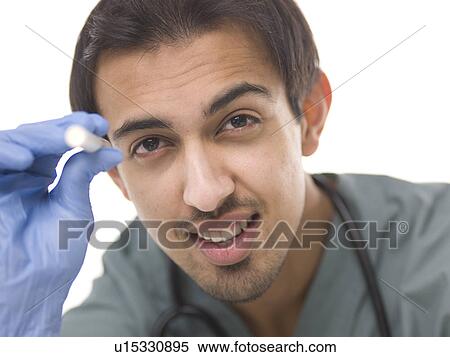 Stock Photography - Young surgeon holding small torch. Fotosearch