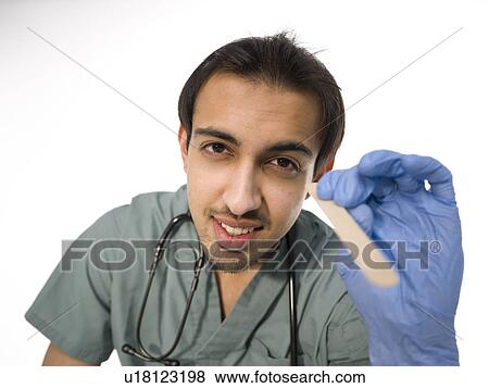 Stock Photo - Young surgeon holding wooden stick for examining patients throat . Fotosearch