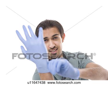 Stock Photo - Young surgeon putting on protective gloves. Fotosearch