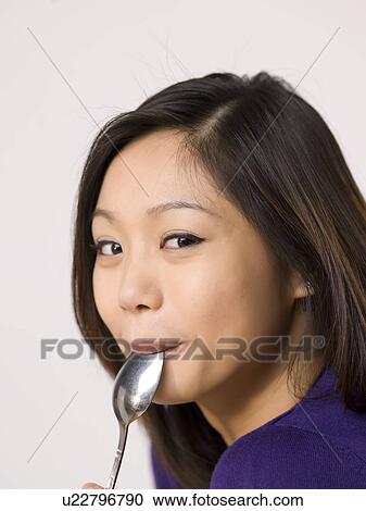 Young woman chewing spoon View Large Photo Image Stock Image - Young woman chewing spoon. Fotosearch