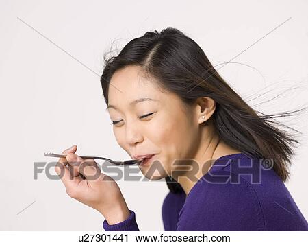 Young woman chewing spoon View Large Photo Image Stock Image - Young woman chewing spoon. Fotosearch
