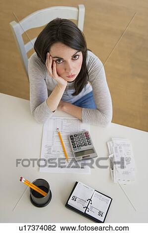 Young woman doing taxes and looking at camera View Large Photo Image Stock Image - Young woman doing taxes and looking at camera. Fotosearch
