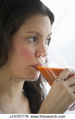 Stock Photo - Young woman drinking carrot juice. Fotosearch