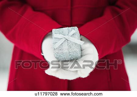 Stock Photo - Young woman holding Christmas gift. Fotosearch