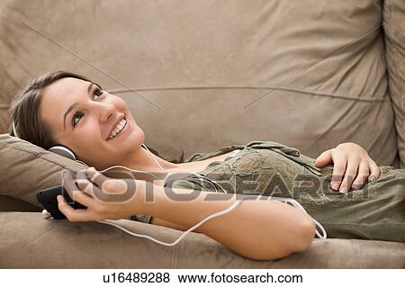 Stock Photo - Young woman listening music from mp3 player. Fotosearch