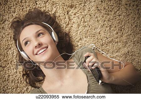 Stock Photography - Young woman listening music from mp3 player. Fotosearch