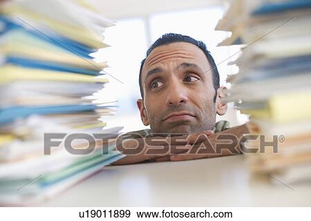 Young woman looking at stack of documents at desk View Large Photo Image Stock Photo - Young woman looking at stack of documents at desk. Fotosearch