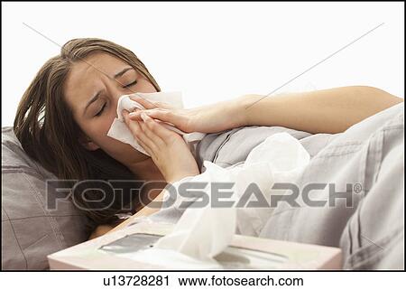 Young woman lying in bed blowing nose View Large Photo Image Stock Image - Young woman lying in bed blowing nose. Fotosearch