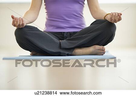 Picture - Young woman meditation in lotus position, low section. Fotosearch