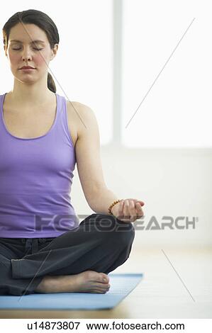 Stock Photo - Young woman meditation in lotus position. Fotosearch