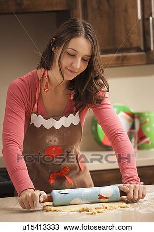 Stock Image - Young woman rolling dough. Fotosearch