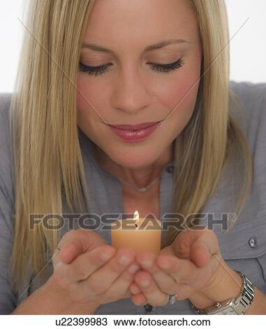 Stock Image - Young woman smelling scented candle. Fotosearch