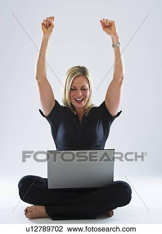Young woman using laptop, celebrating View Large Photo Image Stock Image - Young woman using laptop, celebrating. Fotosearch