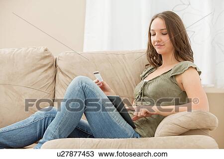 Stock Image - Young woman using tablet and holding credit card. Fotosearch
