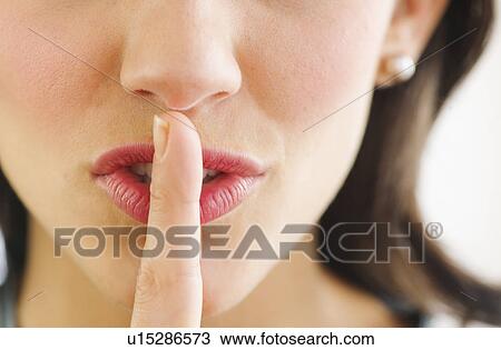 Stock Image - Young woman with finger on lips, close-up. Fotosearch
