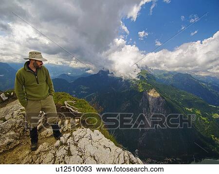 Stock Image - a man standing at the edge of a mountain looking over; veneto, italy. Fotosearch