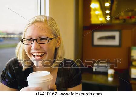 Stock Image - a young woman smiling with coffee at a cafe. Fotosearch