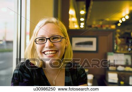 Stock Image - young woman smiling in a cafe. Fotosearch