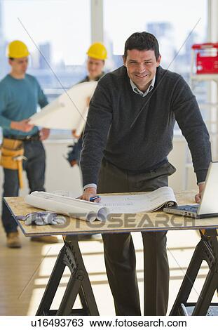 Architect preparing blueprintConstruction workers in background View Large Photo Image Stock Image - Architect preparing blueprintConstruction workers in background. Fotosearch