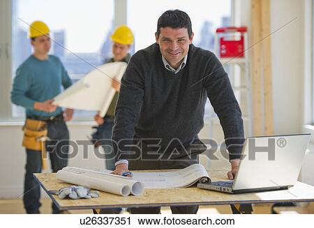 Architect preparing blueprintConstruction workers in background View Large Photo Image Stock Image - Architect preparing blueprintConstruction workers in background. Fotosearch