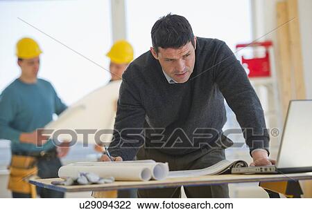 Architect preparing blueprintConstruction workers in background View Large Photo Image Stock Image - Architect preparing blueprintConstruction workers in background. Fotosearch