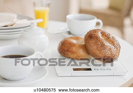 Bagels on weight scale on kitchen table View Large Photo Image Stock Photography - Bagels on weight scale on kitchen table. Fotosearch